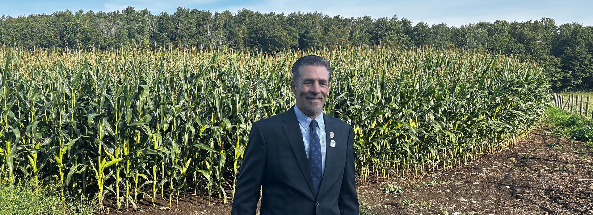 Paul standing in cornfield wearing a suit